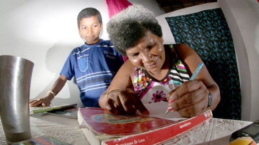 Aos 42, Sandra aprendeu a ler e a escrever com o filho Damião, de 11 (Foto: AGIL FOTOGRAFIA/BBC BRASIL)