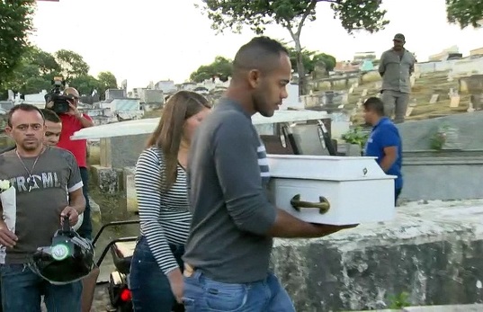 Bebê atingido por bala perdida ainda no útero da mãe é enterrado em cemitério em Duque de Caxias (Foto: Reprodução/TV Globo) Bebê atingido por bala perdida ainda no útero da mãe é enterrado em cemitério em Duque de Caxias (Foto: Reprodução/TV Globo)