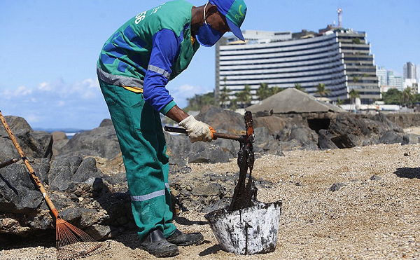 Agente de limpeza recolhe material na praia de Ondina, em Salvador, nesta quinta (Foto: Marina Silva | CORREIO)
