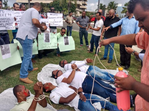 Deitados na grama e segurando cartazes, os manifestantes lembraram a forma cruel como as vítimas morreram: amarradas, amordaçadas e enroladas em sacos de nylon (Foto: Reprodução | A Tarde)