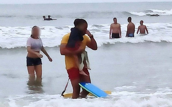 O agente se emocionou e saiu do mar enxugando as lágrimas carregando o pequeno nos braços (Foto: Reprodução)