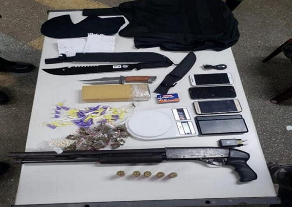 Com o acusado foram encontrados uma espingarda calibre 12, um tablete de maconha e 40 trouxas da droga, 67 pinos de cocaína, 29 balas de crack, cinco cartuchos, uma balança, uma balaclava e três celulares com dois carregadores (Foto: Reprodução)