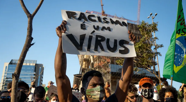 Manifestante levanta cartaz com os dizeres