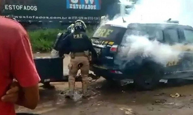 É possível ver o homem preso na mala da viatura aparentemente sendo sufocado com gás (Foto: Reprodução)
