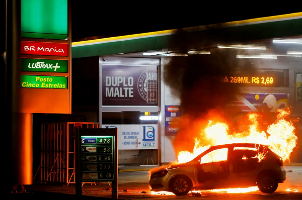 Carro é incendiado em frente a posto de gasolina na noite desta segunda-feira (12), em Brasília (Foto: Adriano Machado/Reuters)