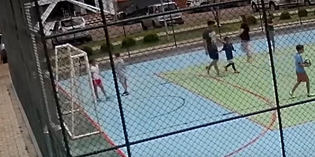 No vídeo, é possível ver o homem segurando os braços do menino para trás afim de que o filho dele, que tinha caído e se machucado, dê um soco no rosto do colega (Foto: Reprodução) No vídeo, é possível ver o homem segurando os braços do menino para trás afim de que o filho dele, que tinha caído e se machucado, dê um soco no rosto do colega (Foto: Reprodução)