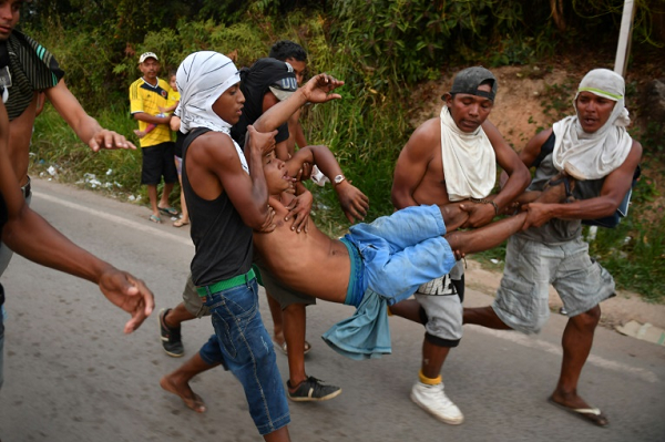 Manifestantes venezuelanos opositores carregam um ferido no lado brasileiro da fronteira com a Venezuela (Foto: Reprodução) Manifestantes venezuelanos opositores carregam um ferido no lado brasileiro da fronteira com a Venezuela (Foto: Reprodução)
